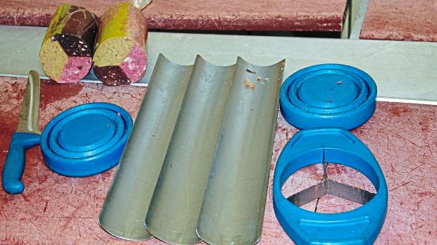 Das Wurstschneidegerät besteht aus sechs Teilen: drei Edelstahl-Schalen, jeweils ein Deckel für oben und unten und ein Messer mit drei Klingen. Das Wurstschneidegerät besteht aus sechs Teilen: drei Edelstahl-Schalen, jeweils ein Deckel für oben und unten und ein Messer mit drei Klingen.